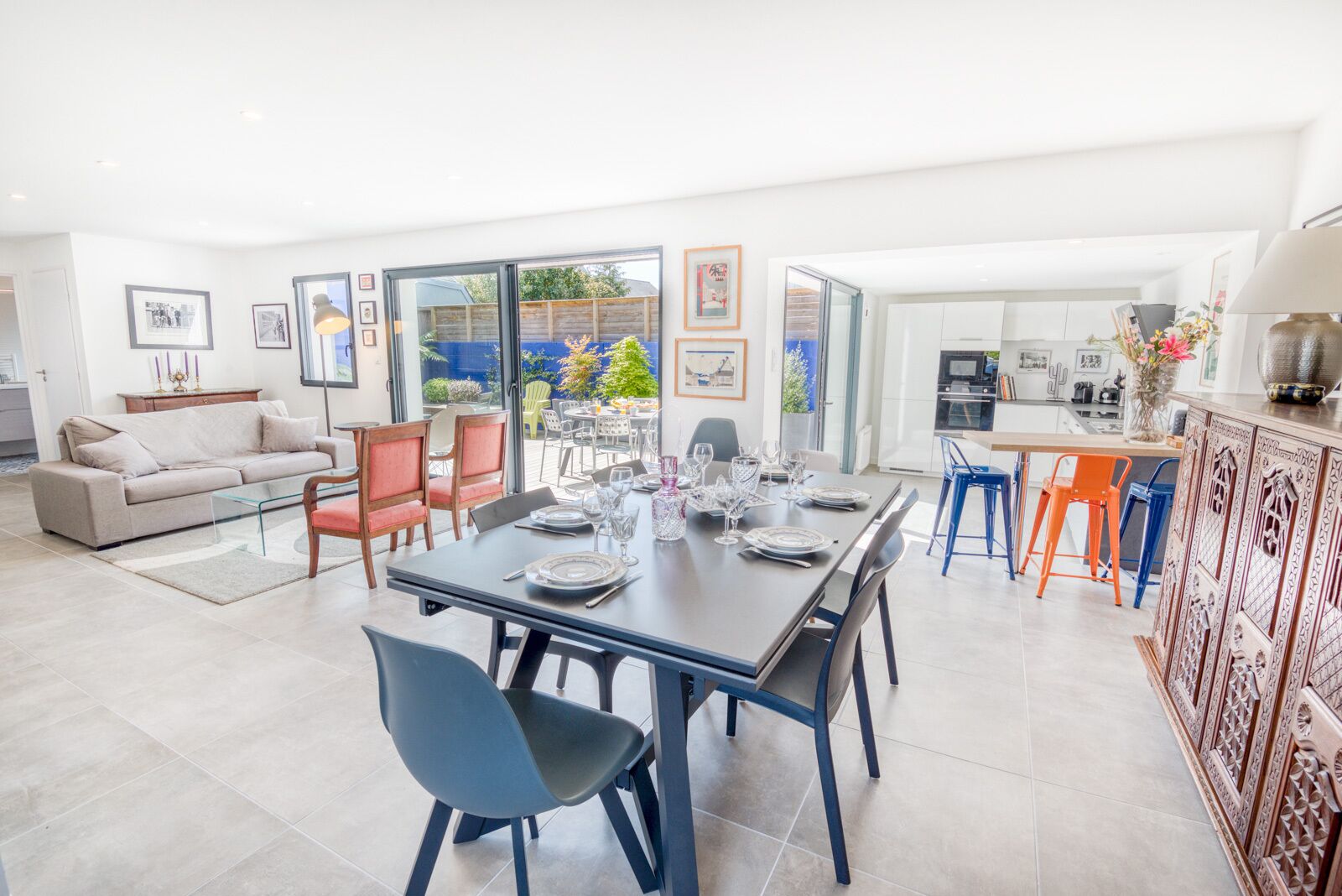 A spacious living area with a dining table set for six, a sofa, and a kitchen area with modern appliances.