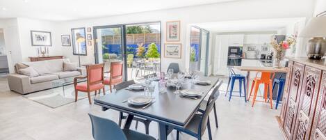 A spacious living area with a dining table set for six, a sofa, and a kitchen area with modern appliances.