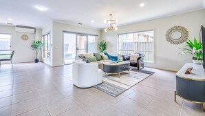 Una sala de estar amplia con sofá, sillón, mesa de centro y mueble para televisión.