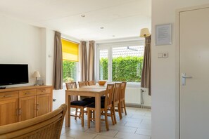 Enjoy casual meals and gatherings in this dining area with a flat-screen TV and large windows offering a view of the surrounding greenery.