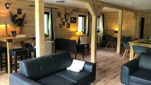 A cozy log cabin interior with a black leather sofa, wooden dining table, and chairs. - Ferienhaus im Sauerland (Winterberg)