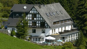 A traditional chalet-style building with a steeply pitched roof, multiple windows, and a balcony. - Ferienhaus im Sauerland (Winterberg)