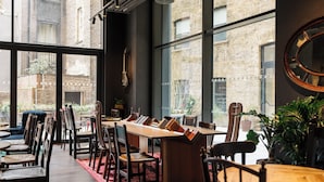 A dining area with a long table, chairs, and a red rug. - Ruby Stella Hotel London by IHG (London)