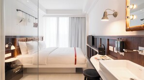 A modern hotel room with a bed, a vanity with a mirror, and a large window with curtains. - Ruby Stella Hotel London by IHG (London)