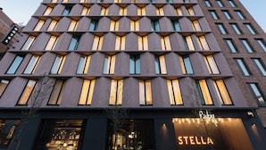 A modern building with a geometric facade, large windows, and a visible storefront with illuminated signage. - Ruby Stella Hotel London by IHG (London)