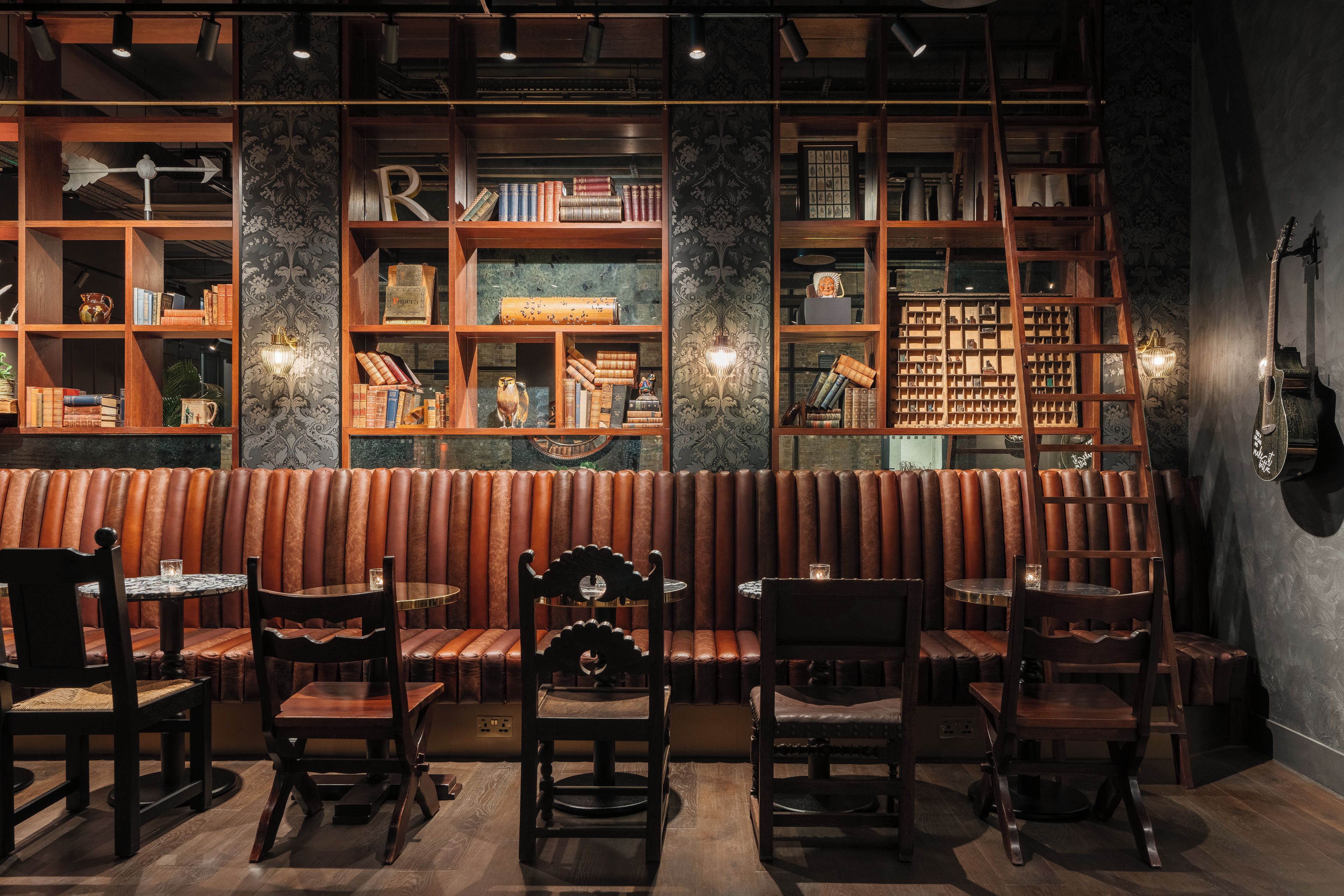 Un restaurant chaleureux avec des étagères en bois, des banquettes en cuir et une variété de livres et d’objets décoratifs.
