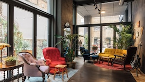 A spacious interior with large windows, a variety of seating options, and a visible brick exterior. - Ruby Stella Hotel London by IHG (London)