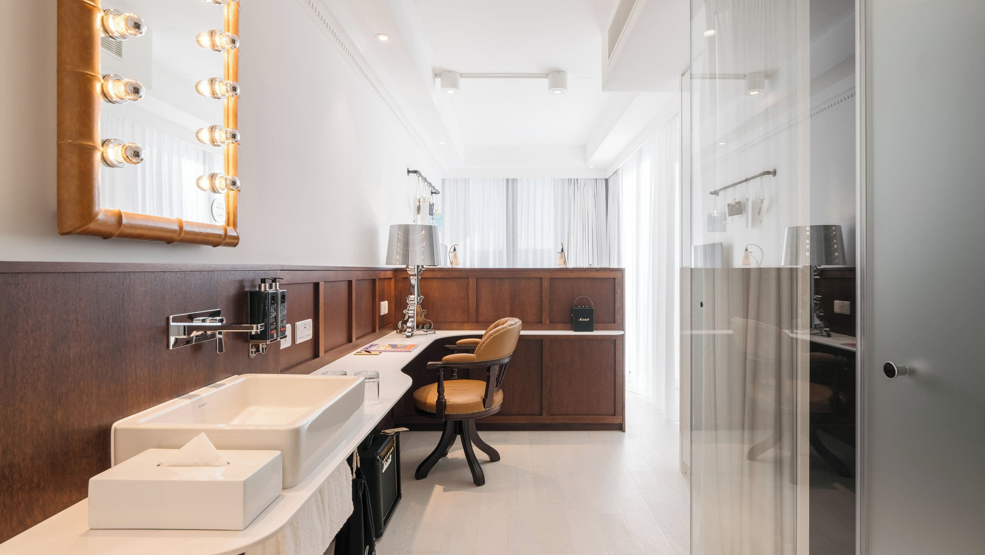 Une salle de bain moderne avec un grand miroir, un meuble-lavabo et une chaise.