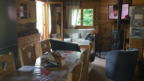 A cozy cabin interior with a dining area, a sofa, a television, and a fireplace.