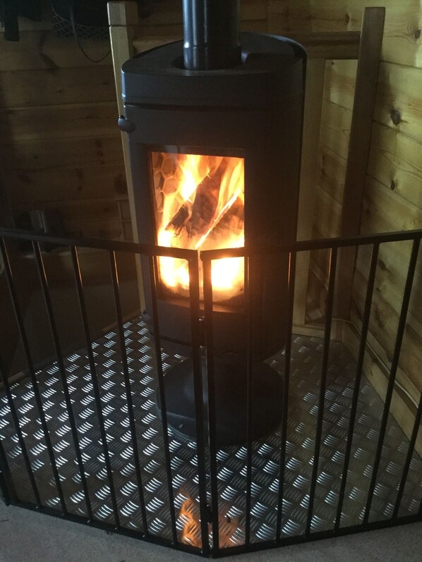 A wood-burning stove in a corner of a room with a metal grate floor. - Chalet 3 Avec vue Imprenable ,sauna et Terrain de Pétanque. Animaux Acceptés (Ventron)