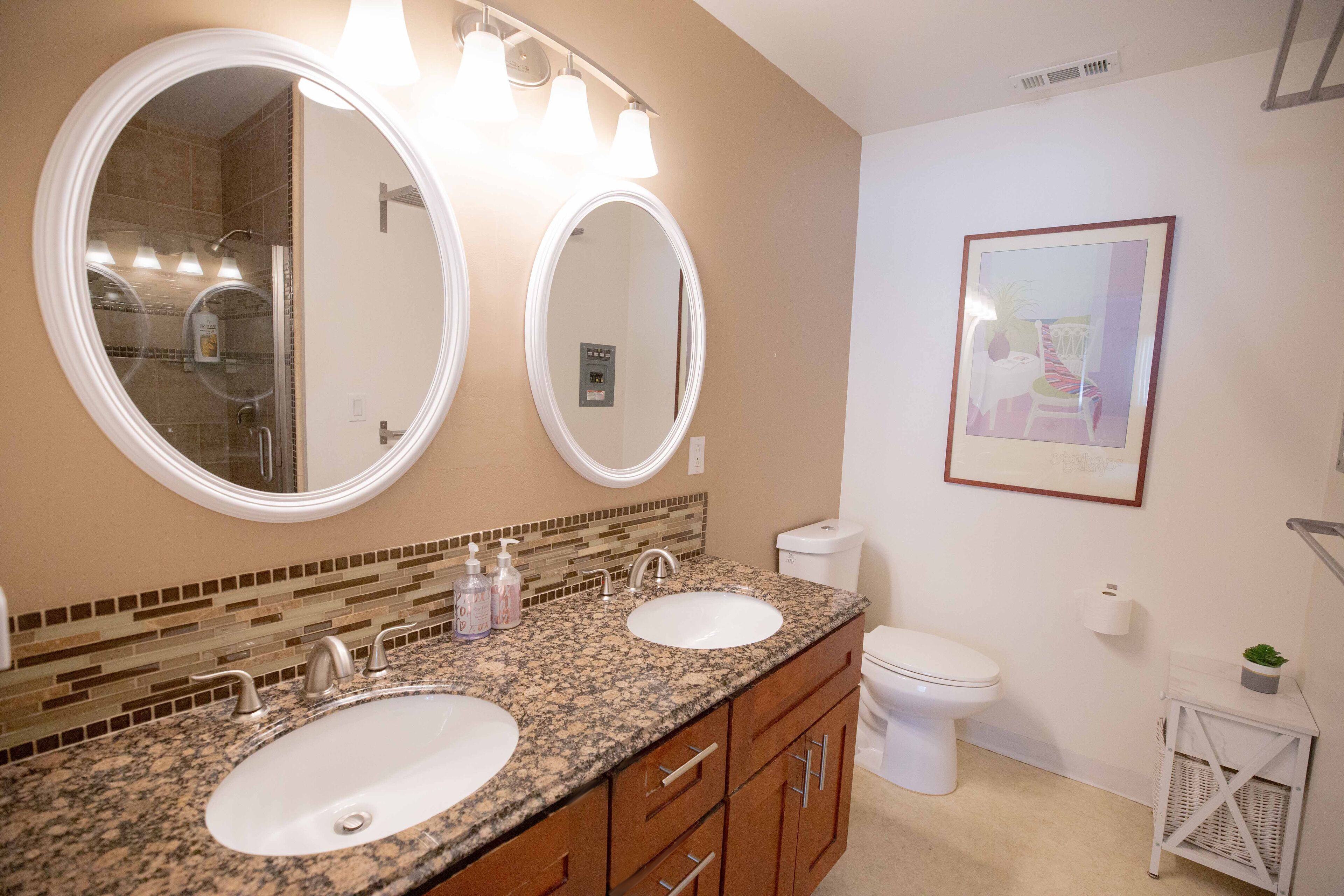 A bathroom with two sinks, a toilet, and a shower.