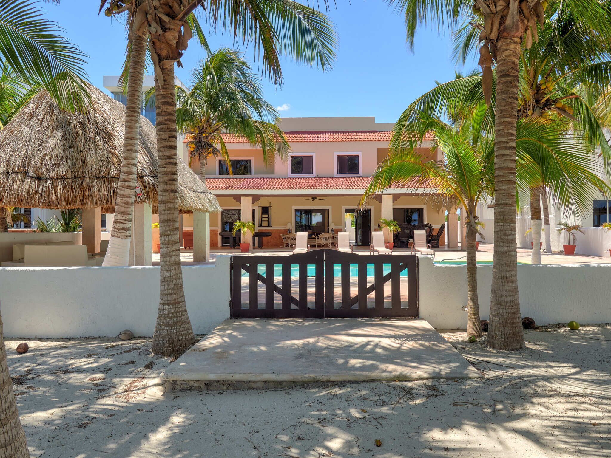A resort with a pool, palm trees, and a building with a red-tiled roof.
