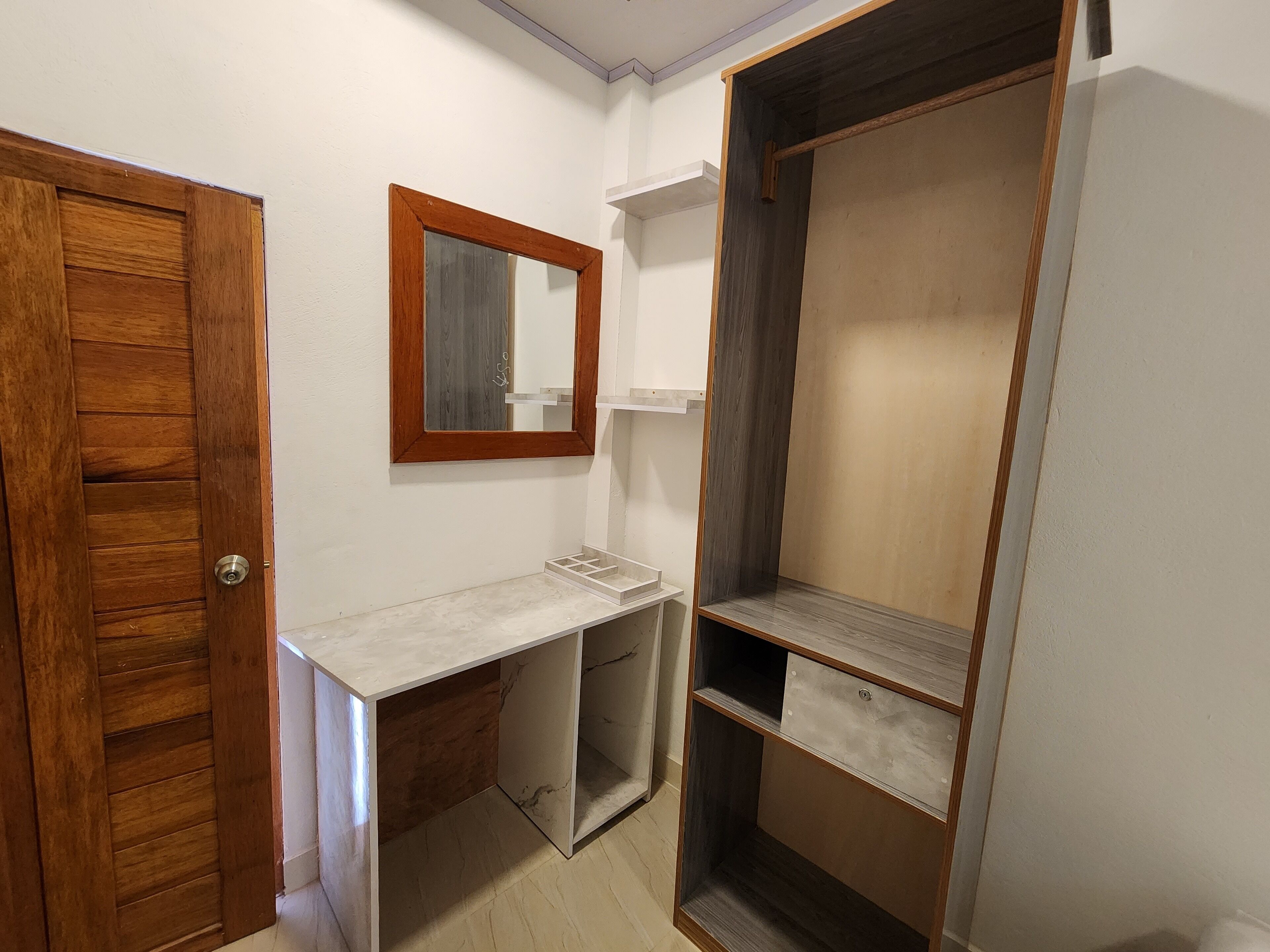 Ein Zimmer mit Holztür, Marmorplatte, Spiegel und fest eingebauten Regalen.