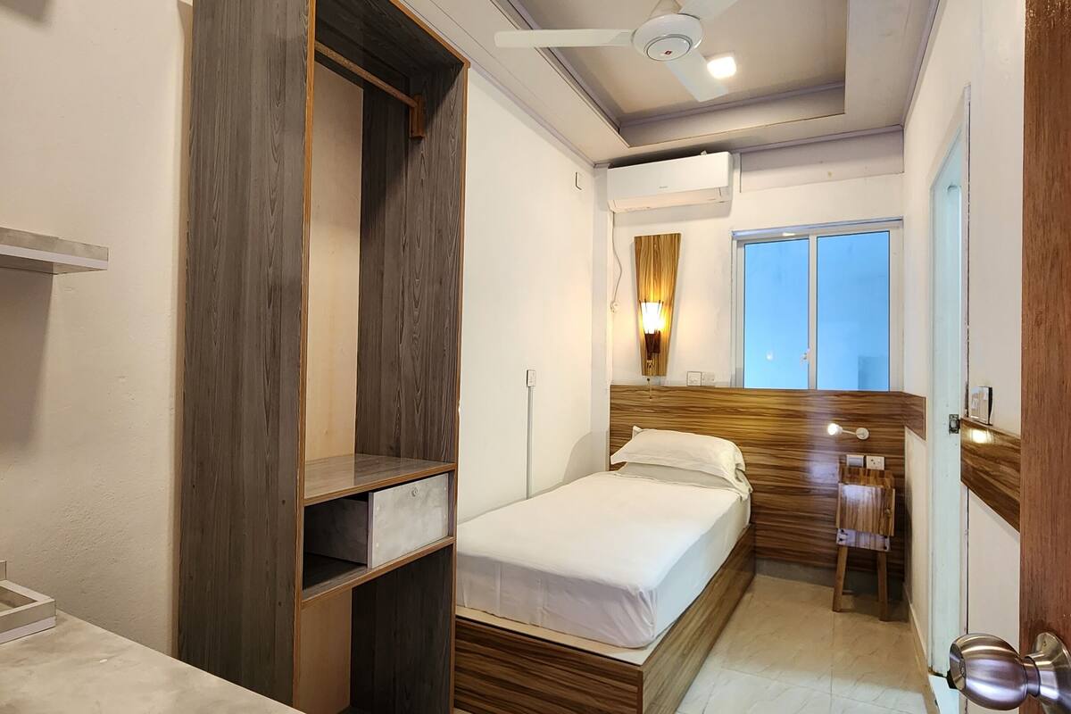 Un dormitorio compacto con cama, mesita de noche, armario y un pequeño escritorio con silla.