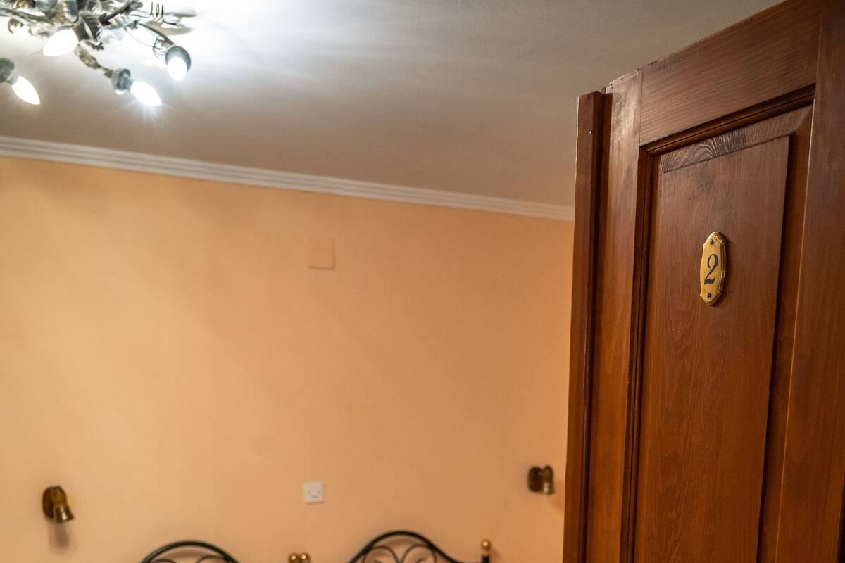 A bedroom with a bed, a wooden door, and a nightstand.