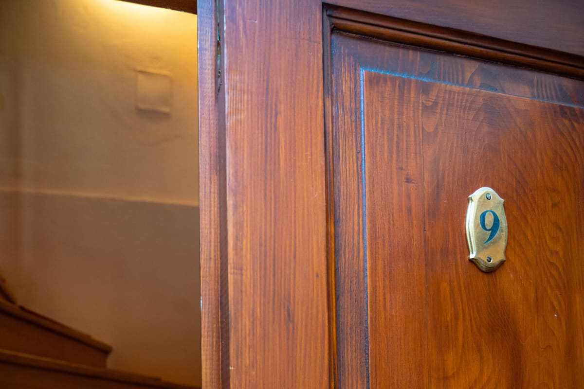 A wooden door with a brass number plate marked '9'.