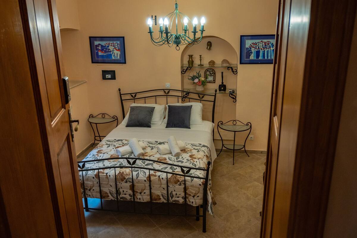 A bedroom with a bed, a chandelier, and two wall-mounted picture frames.
