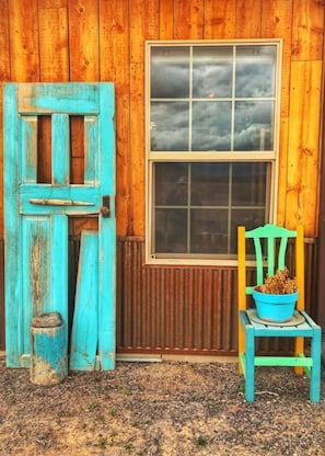 A rustic wooden building with a large window and a blue door. - All 4 Triple View Tiny Homes (Orchard City)