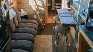 A compact, cabin-style interior with a sofa, dining area, and kitchen.