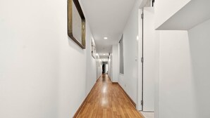 A long, narrow hallway with wooden flooring and white walls. - Chueca Central Residence (Madrid)