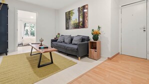 A living room with a sofa, coffee table, and a painting on the wall. - Chueca Central Residence (Madrid)