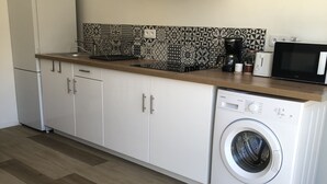 A compact kitchen with a washing machine, a microwave, and a coffee maker. - Appartement de Sylvie (Porto-Vecchio)