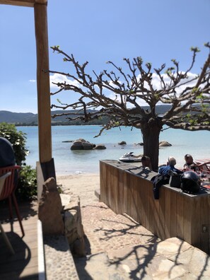 A wooden deck with a stone pathway leading to a seating area overlooking a lake. - Appartement de Sylvie (Porto-Vecchio)