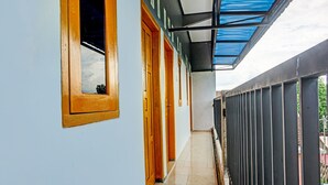 Un pasillo con puertas de madera, piso de baldosas y barandilla de metal.