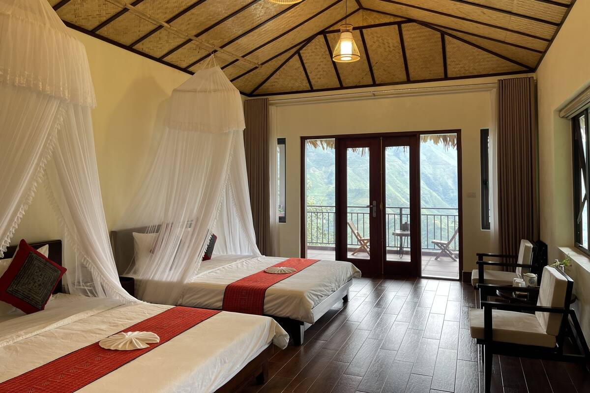 Quarto com duas camas, varanda e vista para as montanhas.