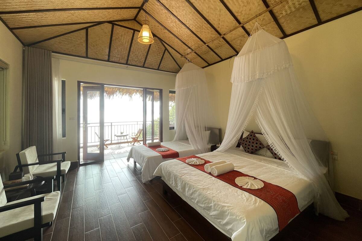 Um quarto espaçoso com uma cama grande, um espaço de estar separado e uma varanda com vista.
