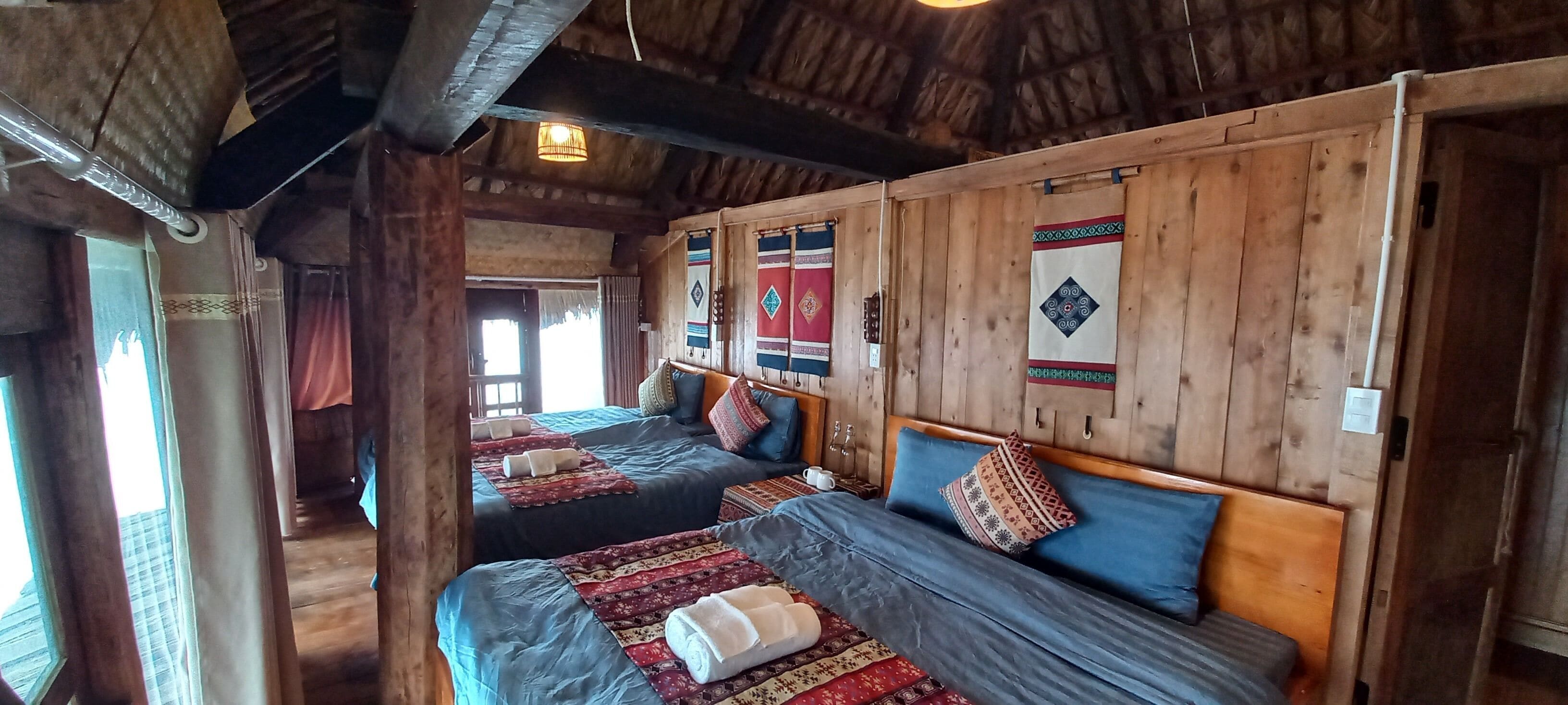 Una camera in legno dallo stile rustico con due letti, ognuno con una coperta e dei cuscini decorati, e un soffitto in legno con travi a vista.