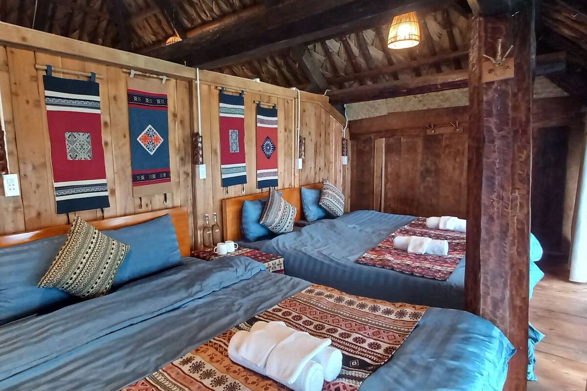 Quarto com duas camas, paredes de madeira e tapeçarias tradicionais.