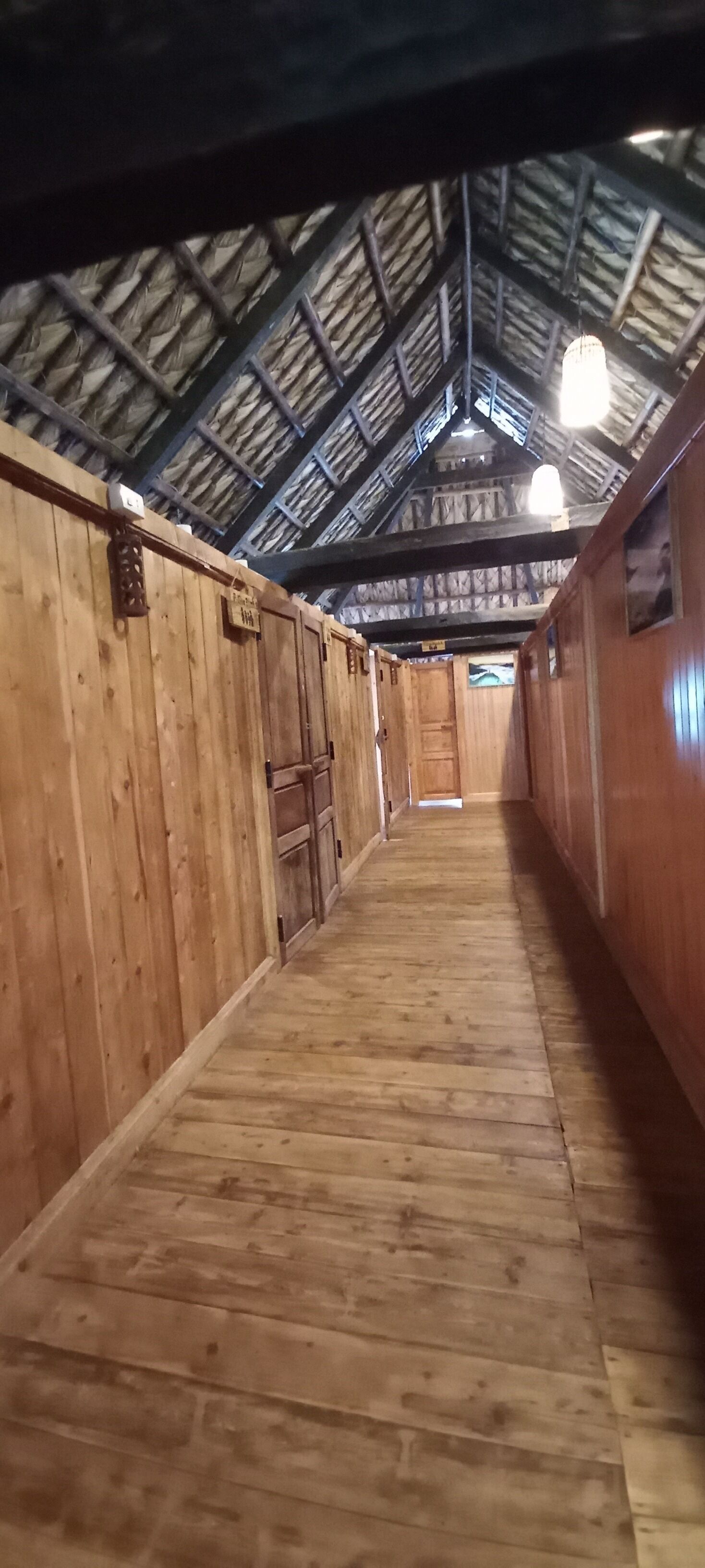 Un largo y estrecho pasillo con paredes de madera y un techo alto e inclinado.