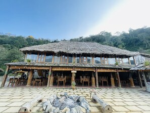 Un edificio rústico de madera con techo de paja, varias ventanas y mesas al aire libre.