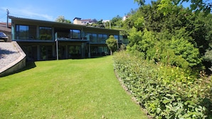 Una casa moderna de dues plantes amb un jardí ben cuidat i vegetació abundant.