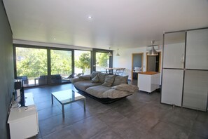 A modern living space with a sofa, a dining table, and a kitchen area. - Apartment with Private Beach in Gerês (Gerês)