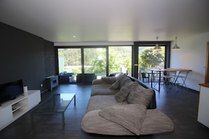 A modern living room with a sectional sofa, a glass coffee table, and a flat-screen TV.