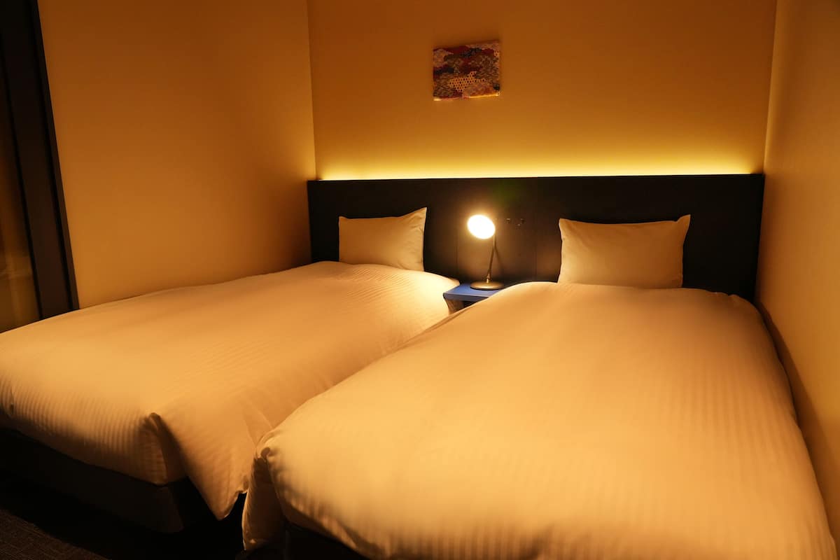 A double bed with a headboard, a bedside table with a lamp, and a small artwork on the wall.