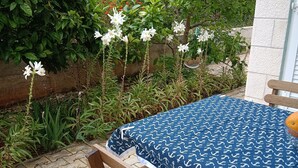 A wooden table with a blue tablecloth featuring a white anchor pattern, set on a patio with a tiled floor. - Blue house apartment Korčula (Žrnovo,)