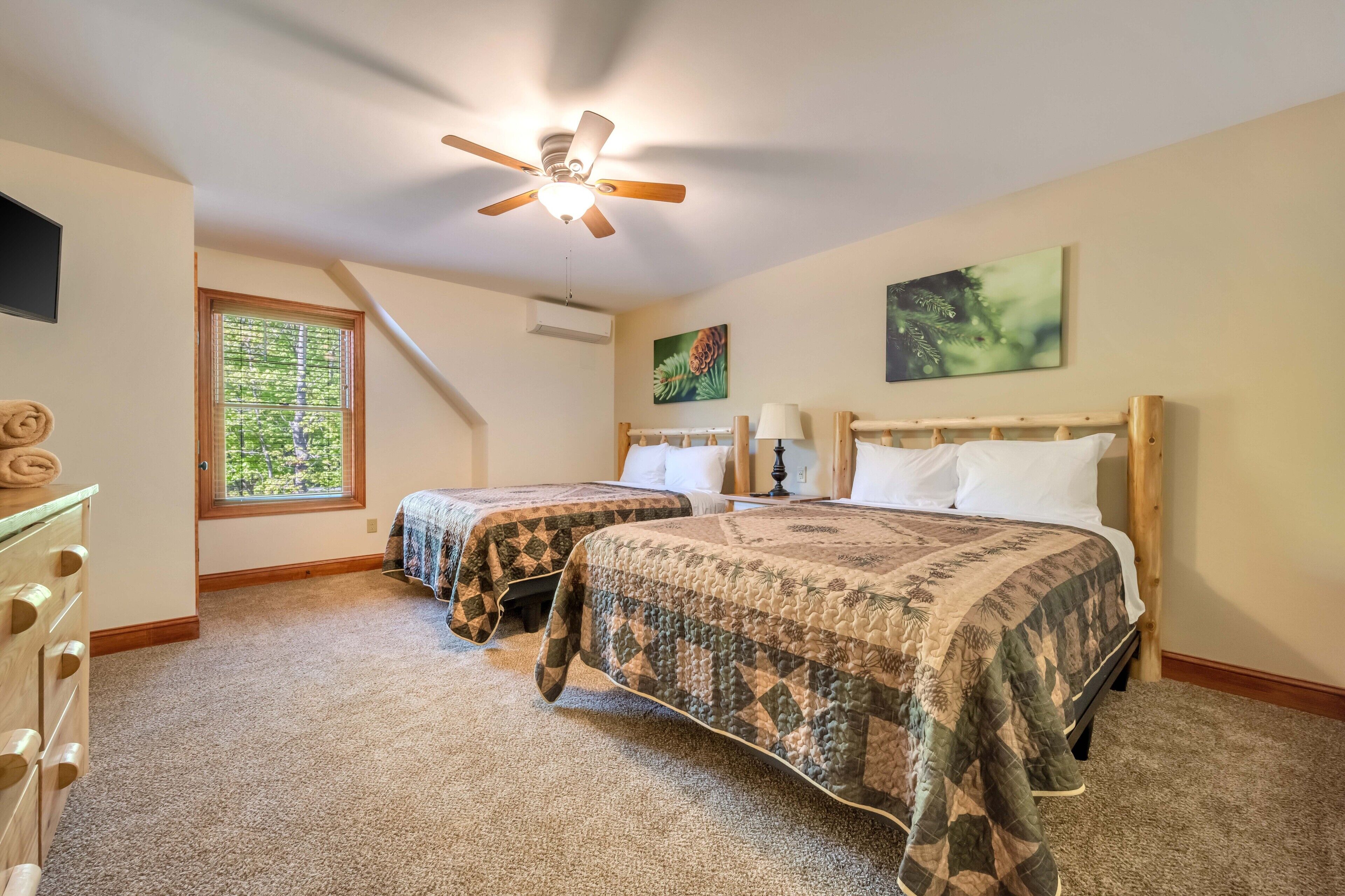 A bedroom with two beds, a ceiling fan, a window with blinds, and a painting on the wall.
