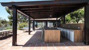 Un espace cuisine extérieur doté d’une pergola, d’une table à manger et de chaises.