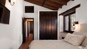 Une chambre à coucher avec un lit, une armoire, une télévision et une fenêtre avec une lampe.