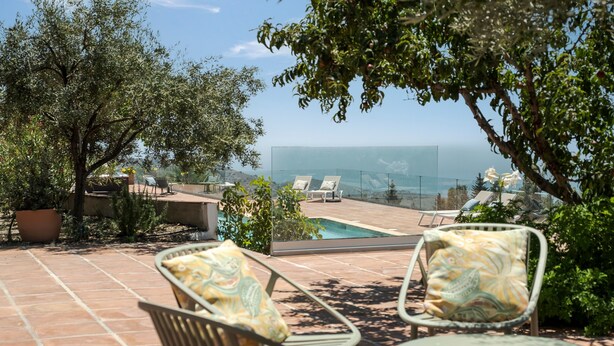 Une terrasse avec des sièges extérieurs, une piscine et une vue sur l’océan.
