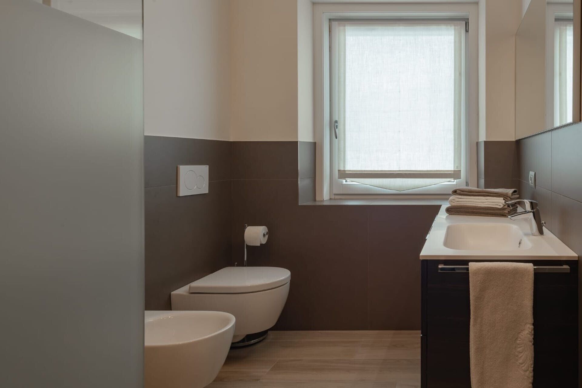 A bathroom with a toilet, sink, and window.