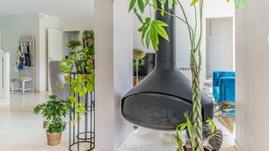 En moderne stue med en stor, sort højttaler, krukkeplanter og en blå sofa.
