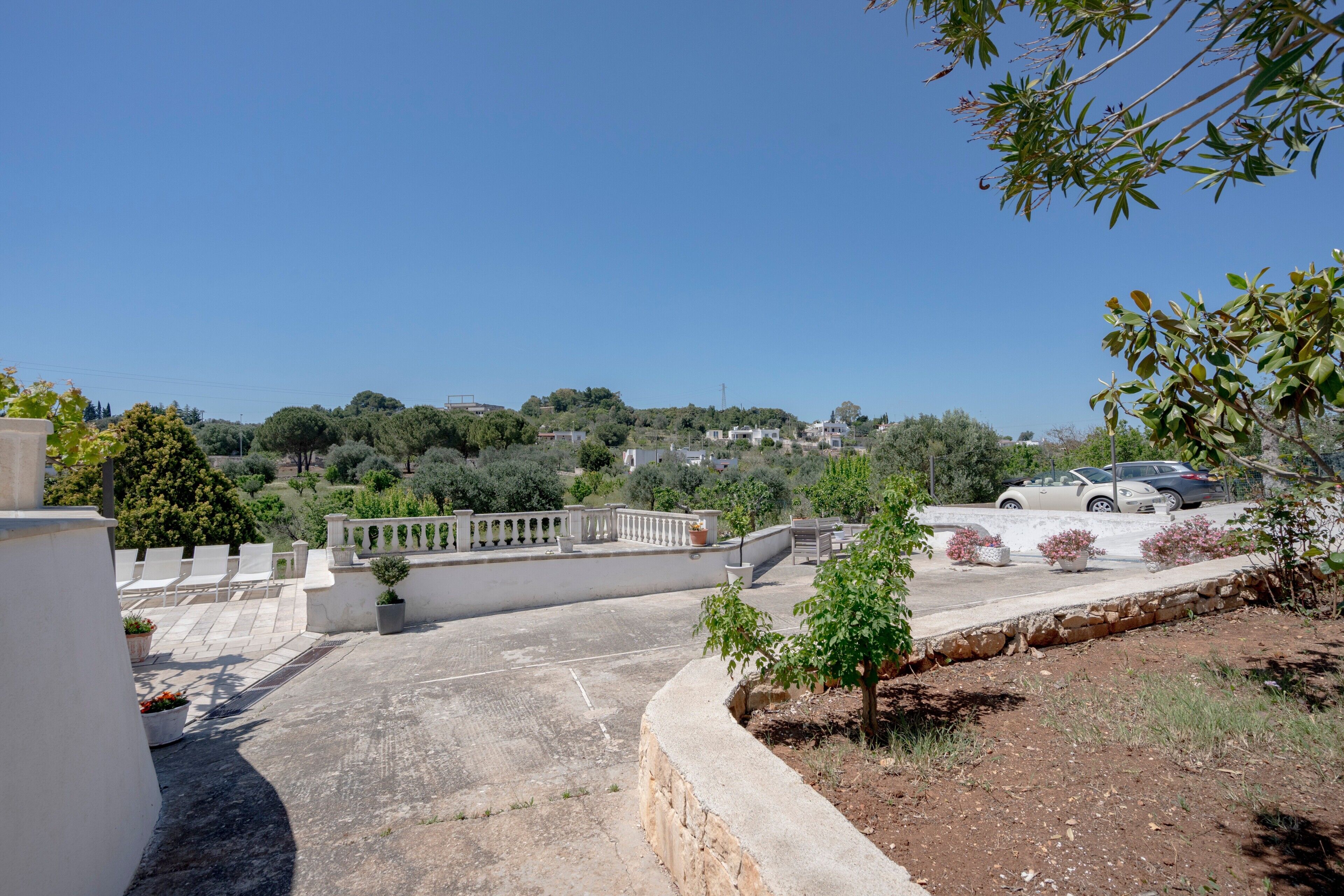 Une terrasse sur le toit offrant une vue sur le paysage environnant, un espace de stationnement et un petit jardin.