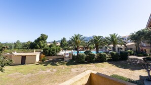 A resort with a swimming pool, palm trees, and a mountainous backdrop.