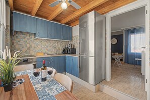 A modern kitchen with blue cabinets, a stainless steel refrigerator, and a tiled backsplash.