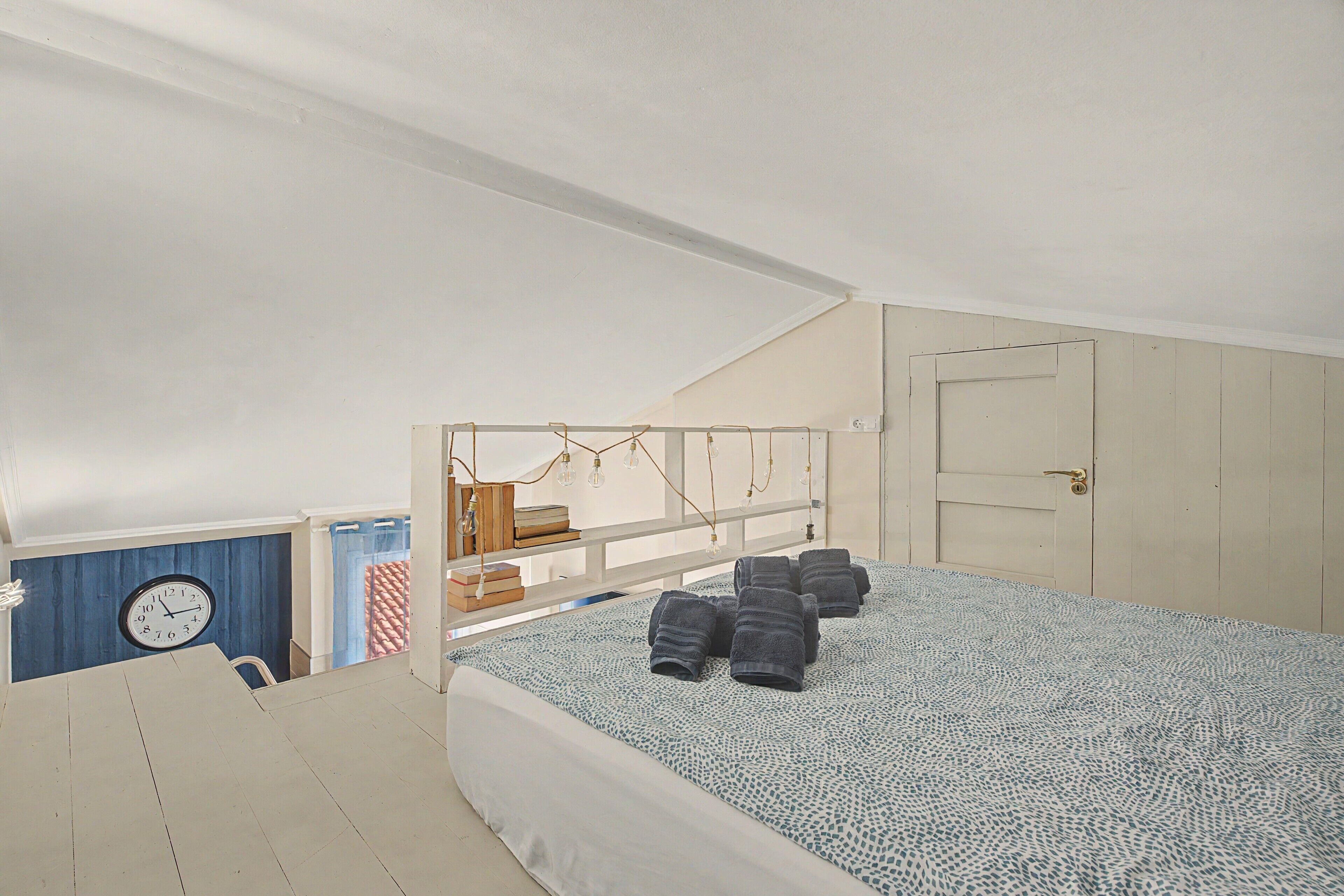 Un dormitorio con una cama, un reloj y una puerta.