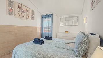 Une chambre à coucher avec un lit, une commode, un miroir et des œuvres d’art accrochées au mur.